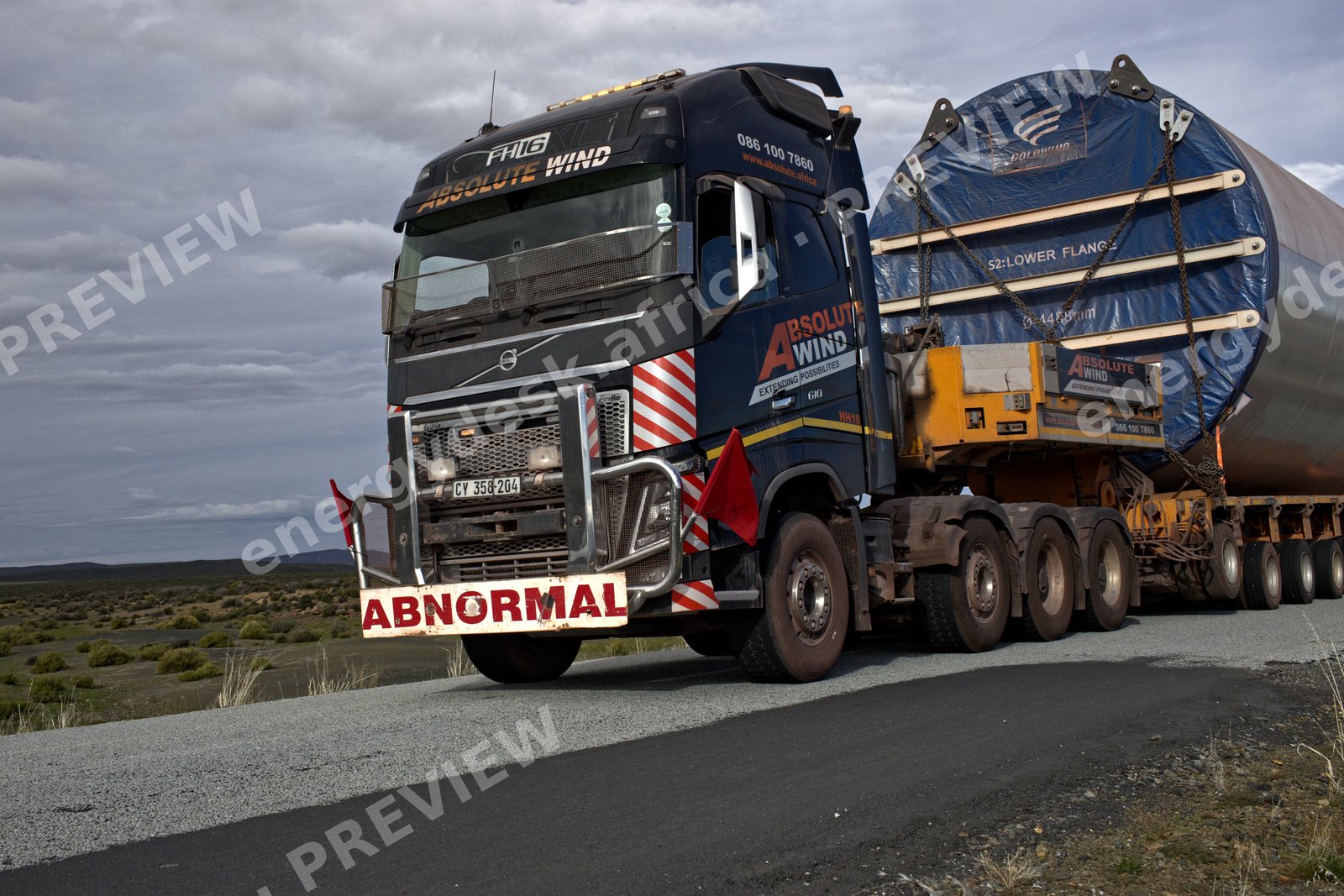 Wind turbine lower tower section on a heavy-haulage trailer at dusk